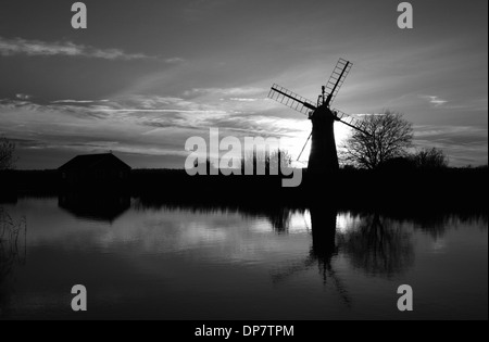 Eine monochrome Ansicht einer Windmühle und Sonnenuntergang mit Reflexionen durch den Fluß Thurne auf den Norfolk Broads, England, Vereinigtes Königreich. Stockfoto