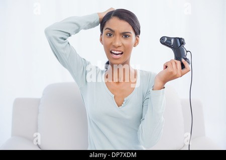 Gereizte hübsche Frau sitzt auf dem Sofa spielen von Videospielen Stockfoto