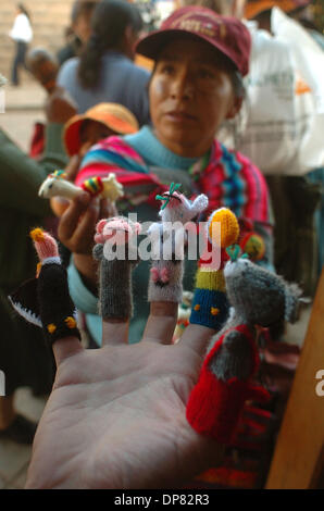 14. Oktober 2006 versucht - Lima, Peru - A Tourist auf Fingerpuppen aus Alpakawolle auf einer Straße in Cusco, Peru, vorgenommen, während die Roaming-Anbieter mit einem Baby auf dem Rücken, der "Gringo" (Ausländer) eine andere Wahl bietet. Indigener Peruaner wie diese Frau haben die touristische Industrie rentabler und zuverlässiger als ihre traditionellen landwirtschaftlichen Arbeit außerhalb der größeren Citi gefunden. Stockfoto