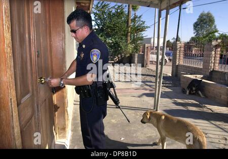 (Veröffentlichten 13.03.2005, a-14) Mexicali Polizist JOSE MONTOYA öffnet seine Haustür, wenn er nach Hause kommt von der Arbeit mit einem automatischen Gewehr. Auf der rechten Seite sind zwei der er und seine Frau vier Wachhunde.  U/T Foto CHARLIE NEUMAN Stockfoto