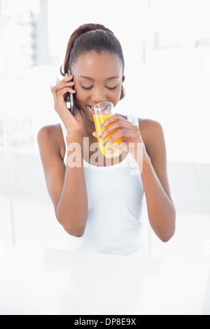 Glückliche athletische Frau telefonieren beim Orangensaft trinken Stockfoto