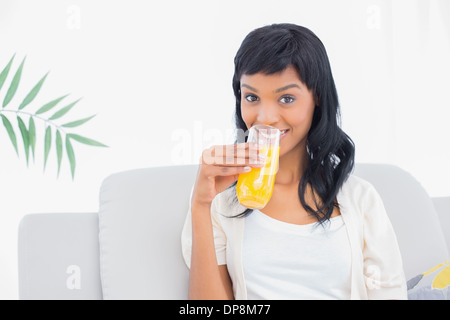 Charmante schwarz behaarte Frau in weißen Kleidern Orangensaft trinken Stockfoto