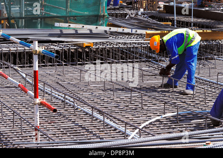 Ein Stahl Fixiermittel sorgfältig binden verstärkt Stahlstäbe in Lage in Vorbereitung für den Bau einer Betonplatte Stockfoto