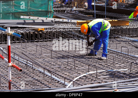 Ein Stahl Fixiermittel sorgfältig binden verstärkt Stahlstäbe in Lage in Vorbereitung für den Bau einer Betonplatte Stockfoto