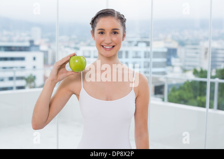 Fröhliche sportliche Brünette mit grünem Apfel Stockfoto