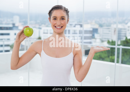 Fröhliche sportliche Brünette hält grüne gesunde Apfel Stockfoto