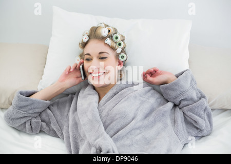 Freuen uns entspannt blonde Frau in Lockenwicklern einen Anruf tätigen Stockfoto