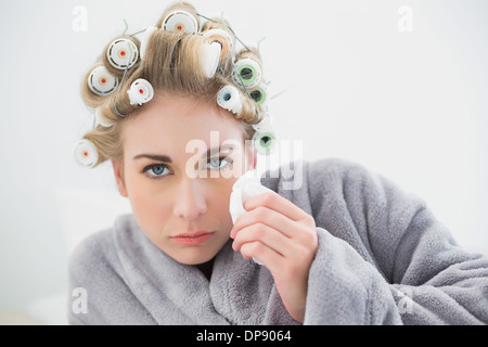 Unruhigen blonde Frau in Lockenwicklern weinend und mit Gewebe Stockfoto