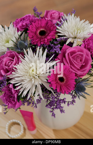 Thistle Sea Holly Eryngium Bourgatii, Cerise Gemini, rosa Aqua Roses, lila Limonium, rosa Nelken und weiße Anastasia in einer Vase in einer häuslichen Umgebung Stockfoto