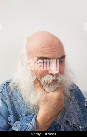 Nachdenklicher senior Mann blickte auf grauem Hintergrund Stockfoto