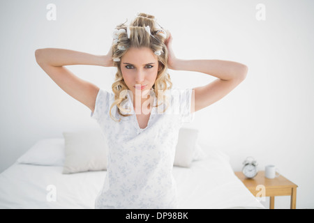 Glücklich attraktive Blondine trägt Lockenwickler posiert Stockfoto