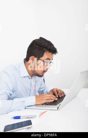 Konzentrierte Geschäftsmann mit Laptop beim hören von Musik in office Stockfoto