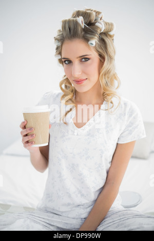 Friedliche hübsche Blondine trägt Lockenwickler halten Kaffee Stockfoto