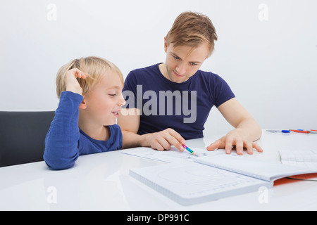 Mitte erwachsenen Mannes unterstützen junge in Studien am Tisch Stockfoto