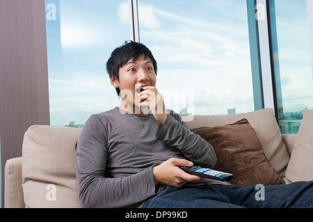 Überrascht mittleren Erwachsenenalter Mann vor dem Fernseher zu Hause auf sofa Stockfoto