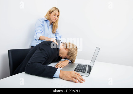 Unternehmerinnen mit überlasteten Kollegen am Schreibtisch im Büro Stockfoto