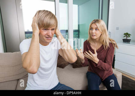 Frau versucht zu sprechen, da Man laut im Wohnzimmer zu Hause schreit Stockfoto