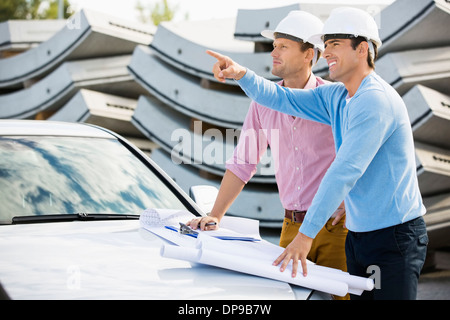 Architekten mit Blaupausen auf Auto diskutieren am Standort Stockfoto