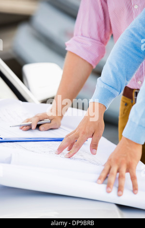 Bild des Architekten mit Blaupausen auf Auto am Standort zugeschnitten Stockfoto