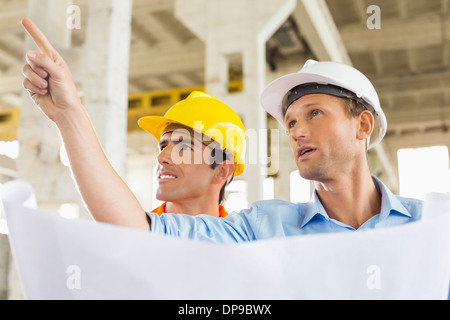 Männliche Architekt erklärt Bauplan an Kollegen auf Baustelle Stockfoto