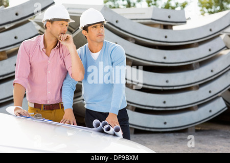 Architekten mit Blaupausen auf Auto arbeitet auf Baustelle Stockfoto