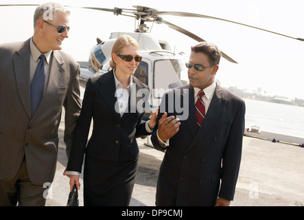 Geschäftsleute, die Kommunikation mit Hubschrauber im Hintergrund Stockfoto