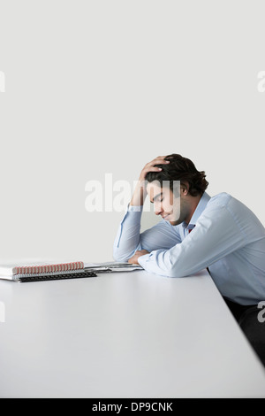 Traurig junger Geschäftsmann stützte sich auf den Schreibtisch im Büro Stockfoto