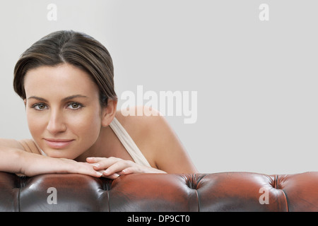 Portrait der schönen Frau auf Sofa vor grauem Hintergrund Stockfoto