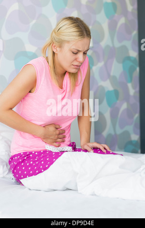 Junge Frau mit Bauch Schmerzen im Schlafzimmer Stockfoto