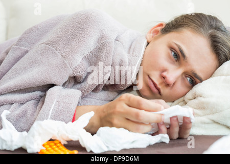 Kranke Frau mit Gewebe und Medikamente auf Bett liegend Stockfoto