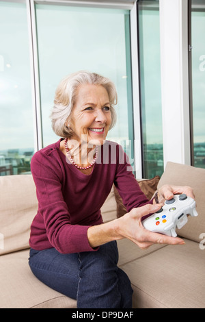 Glückliche senior Frau Videospiel zu Hause auf sofa Stockfoto