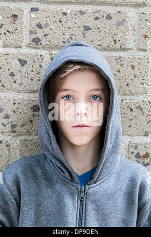 Porträt von einem Teenager mit grauen Hoodie Sweatshirts stand vor einer Wand. Stockfoto