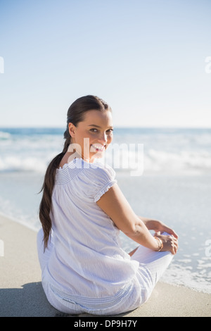 Rückansicht des lächelnden Frau auf dem Strand mit Blick über die Schulter in die Kamera Stockfoto