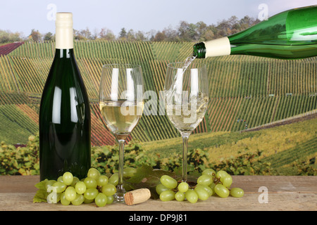 Weißwein aus der Flasche in ein Glas Wein in den Weinbergen gießen Stockfoto