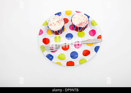 Erhöhte Ansicht von Cupcakes in bunten Teller vor weißem Hintergrund Stockfoto