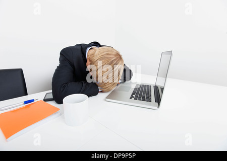 Mitte adult Geschäftsmann von Laptop am Schreibtisch im Büro schlafen Stockfoto