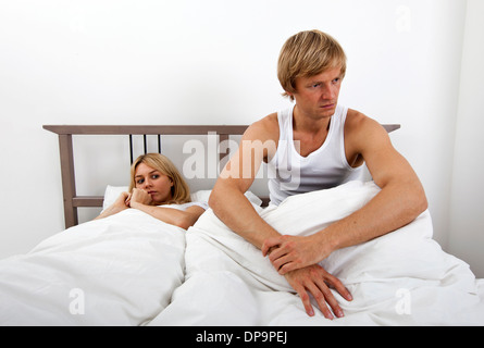 Verärgerter Mann sitzt auf dem Bett mit Frau im Haus Stockfoto