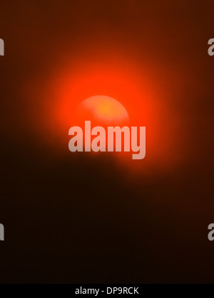 Rauch von Waldbränden schafft ein ungewöhnliche unheimliches orange leuchten, die untergehende Sonne. Stockfoto