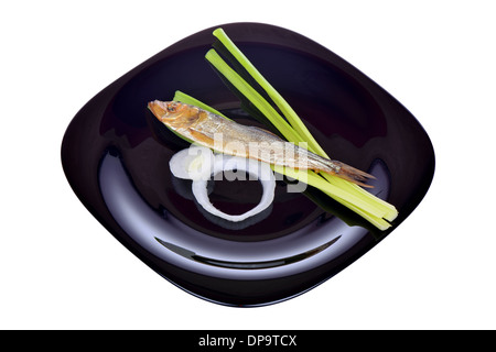 Geräucherter Fisch und Zwiebeln auf einem schwarzen Teller Stockfoto