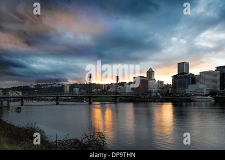 Sonnenuntergang über Portland Oregon Innenstadt entlang Willamette River mit Sonnenstrahlen und Wolken zwischen Hawthorne Bridge Stockfoto