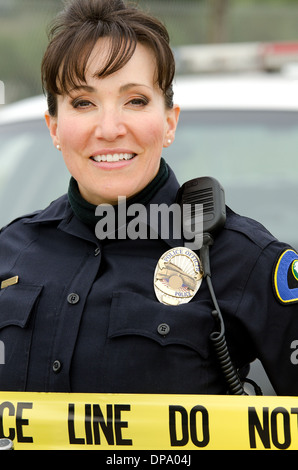 ein Hispanic Polizistin lächelnd vor ihrem Polizeiauto. Stockfoto