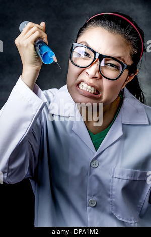 wütend verrückt asiatischen Arzt mit einer Spritze, die Aufnahmen im studio Stockfoto