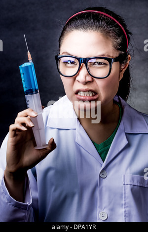 wütend verrückt asiatischen Arzt mit einer Spritze, die Aufnahmen im studio Stockfoto