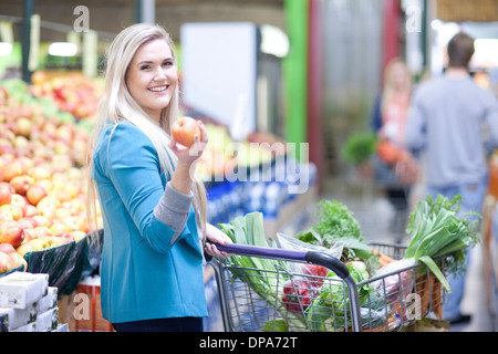 Junge Frau mit Apfel in der Markthalle Stockfoto