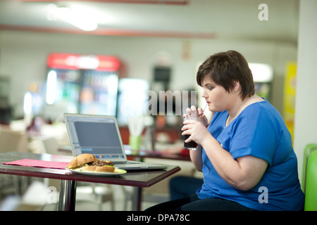 Junge Frau trinkt Cola im café Stockfoto