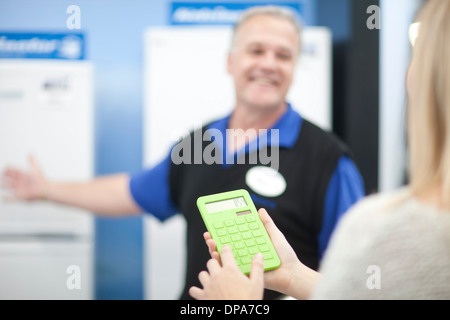 Junge Frau mit Taschenrechner im showroom Stockfoto