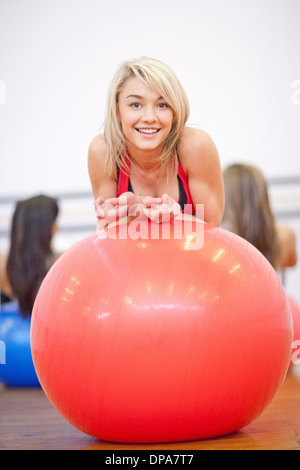 Junge Frau ruht auf Gymnastikball in Aerobic-Kurs Stockfoto