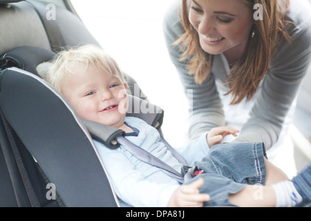Mutter Überprüfung Baby Sohn im Rücksitz des Wagens Stockfoto