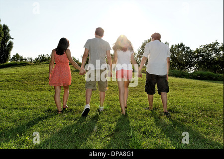 Gruppe junger Erwachsener zu Fuß und Hand in Hand Stockfoto