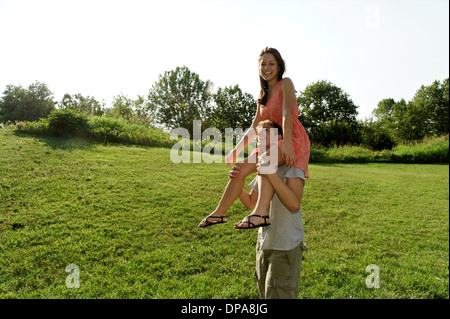 Junge Frau sitzt auf junge mans Schultern Stockfoto